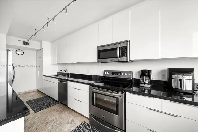 a kitchen with stainless steel appliances granite countertop a stove a refrigerator and a microwave