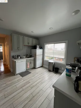 a kitchen with stainless steel appliances a refrigerator a sink a stove and white cabinets with wooden floor