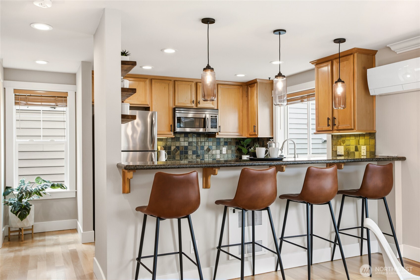 2635 Northwest 57th Street, Unit B Seattle, WA 98107 - Photo 9 of 28 a kitchen with stainless steel appliances kitchen island granite countertop a table chairs in it and kitchen view