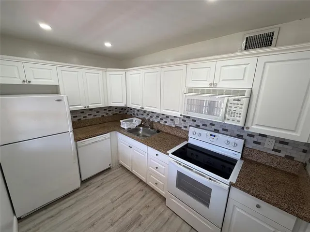 a kitchen with granite countertop white cabinets and white appliances