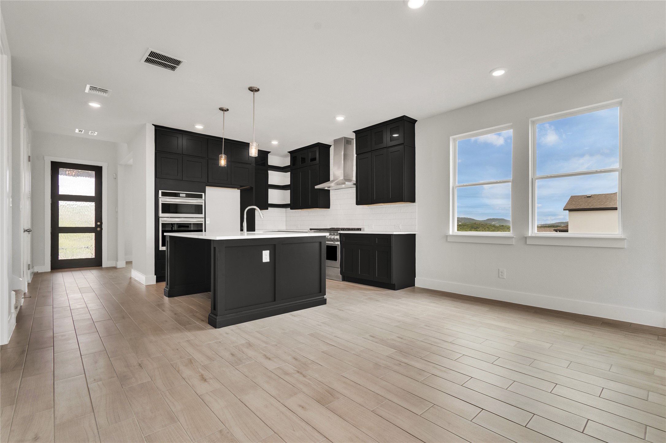 8500 Red Bottle Brush Road Lago Vista, TX 78645 - Photo 10 of 33 An open-concept living space highlights a modern kitchen with sleek black cabinetry and a bright, airy atmosphere.