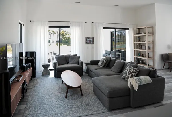 a living room with furniture a floor to ceiling window and a flat screen tv