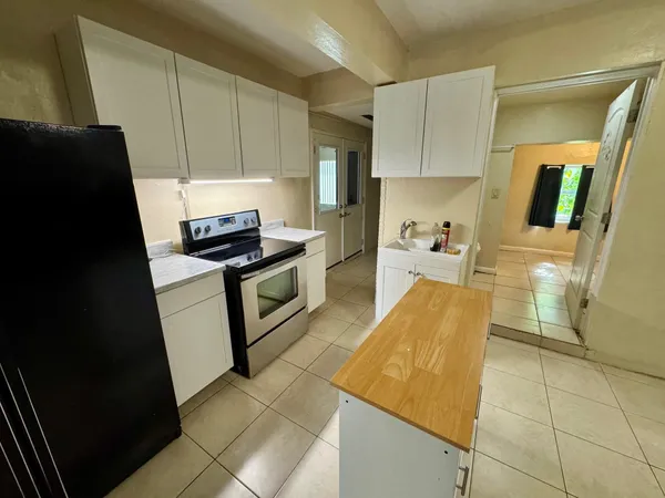 a kitchen with granite countertop a stove a sink and a refrigerator