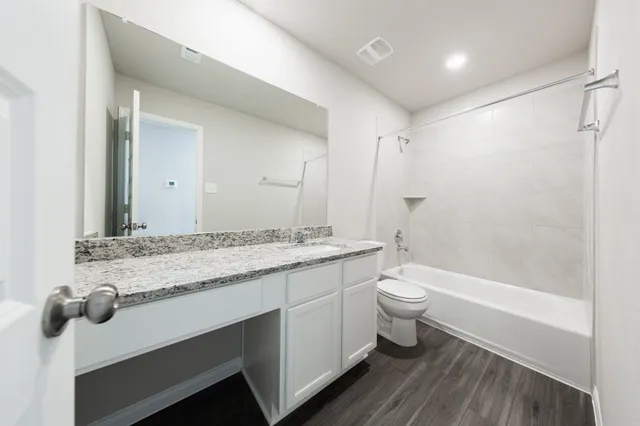 a bathroom with a granite countertop sink a toilet a mirror and shower
