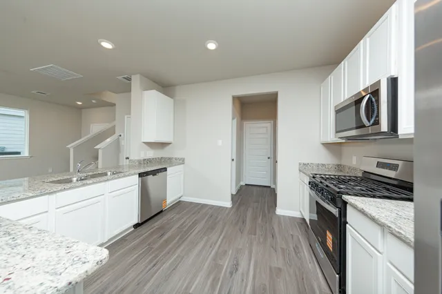 a kitchen with stainless steel appliances a stove a sink cabinets and a wooden floor