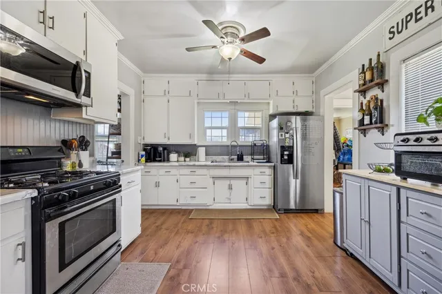 a kitchen with stainless steel appliances white cabinets a sink a stove a refrigerator and microwave