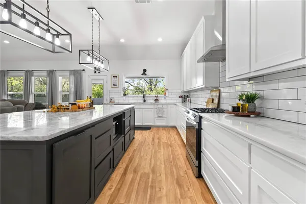 a kitchen with stainless steel appliances granite countertop wooden cabinets a sink dishwasher a stove and a wooden floors