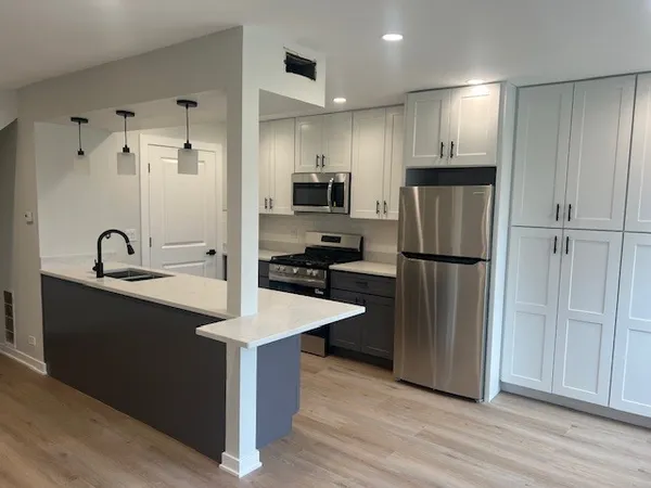 a kitchen with kitchen island a sink appliances and cabinets
