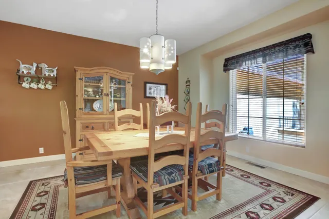 a view of a dining room and livingroom with furniture wooden floor a rug a fireplace and a chandelier