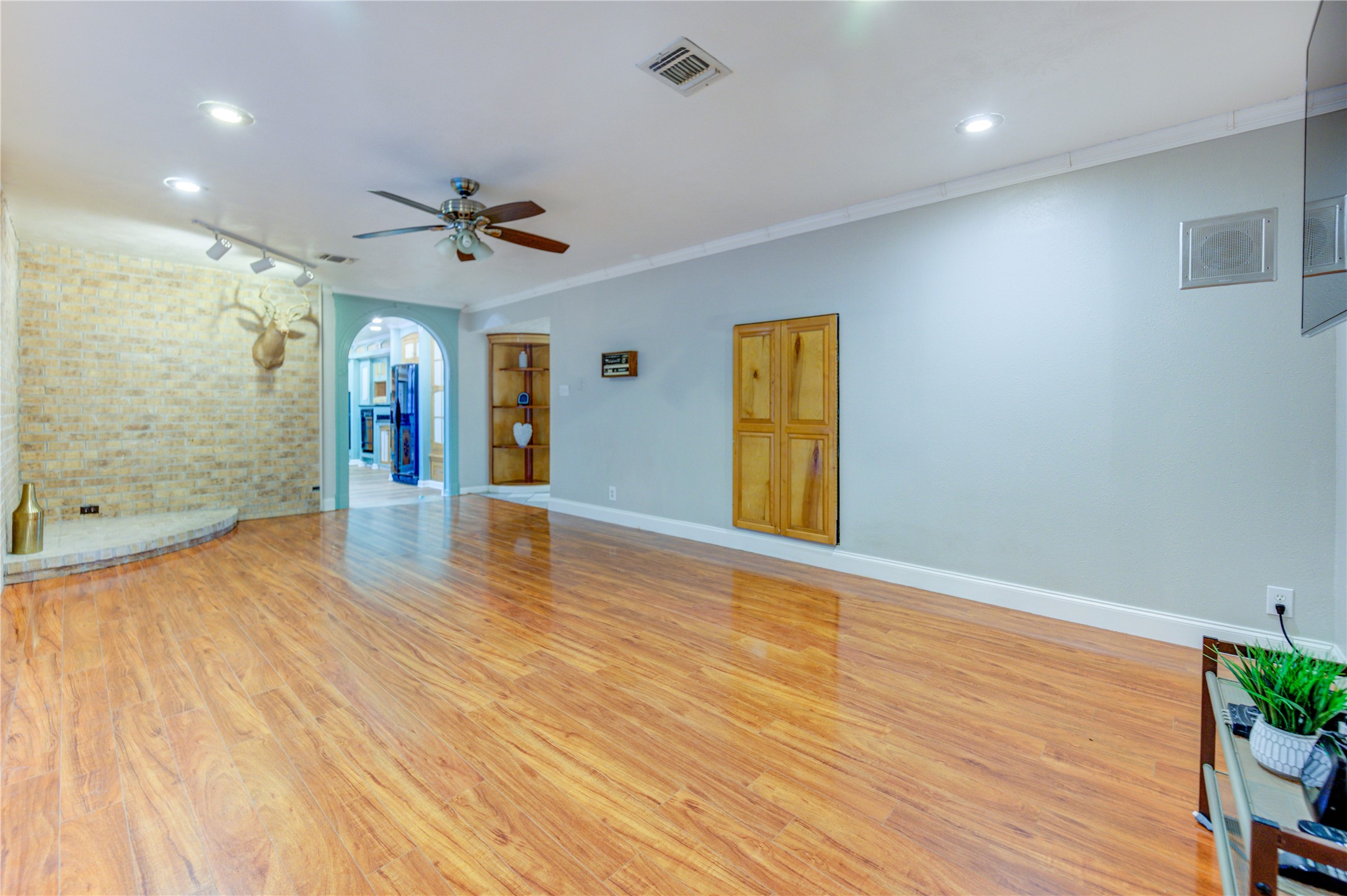 24316 East Webb Road Porter, TX 77365 - Photo 11 of 14 Spacious living area with hardwood floors, recessed lighting, and a ceiling fan. Features a brick accent wall with a decorative niche.