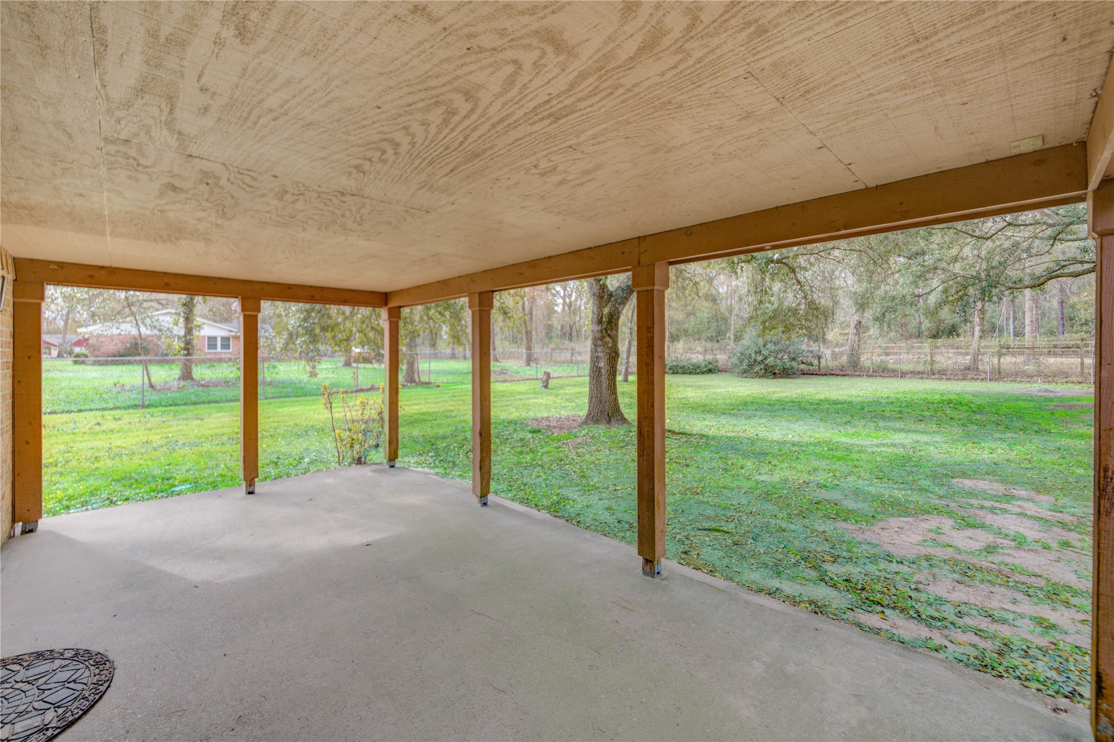 24316 East Webb Road Porter, TX 77365 - Photo 4 of 14 Huge covered patio with a concrete floor, overlooking a large, lush green backyard with mature trees, perfect for outdoor relaxation and entertainment.