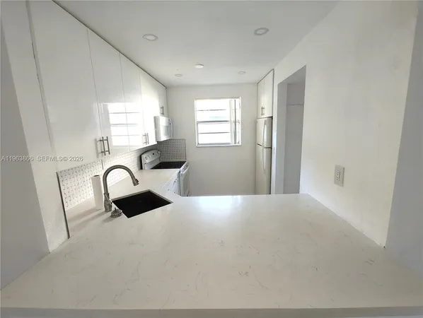 a kitchen with stainless steel appliances granite countertop a sink a stove a refrigerator a window with white cabinets