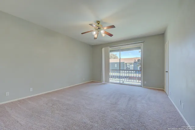 an empty room with a chandelier fan and windows