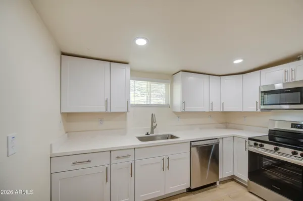 a kitchen with white cabinets sink and stainless steel appliances