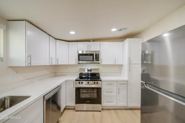 a kitchen with white cabinets and stainless steel appliances