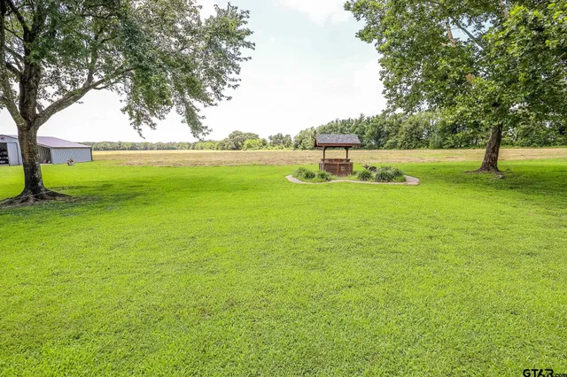 a view of a big house with a big yard and large trees