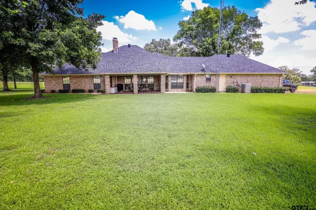 a view of a big house with a big yard and large trees