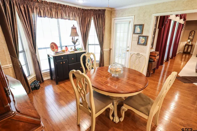 a dining room with stainless steel appliances furniture a rug and a kitchen view