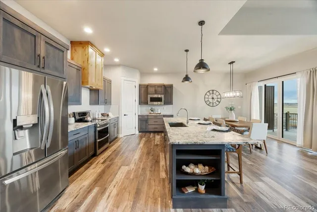 a large kitchen with a table chairs stainless steel appliances and cabinets
