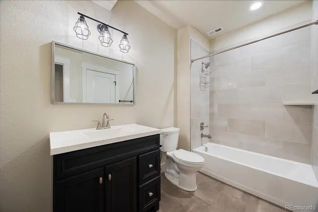 a bathroom with a toilet a sink a mirror a bathtub and vanity