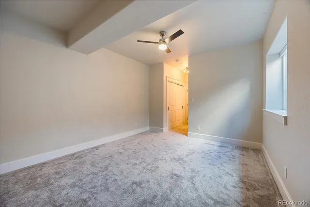 an empty room with a yellow fan and a window