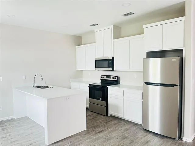 a kitchen with a refrigerator sink and white cabinets