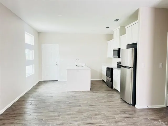 a view of a kitchen with refrigerator and wooden floor