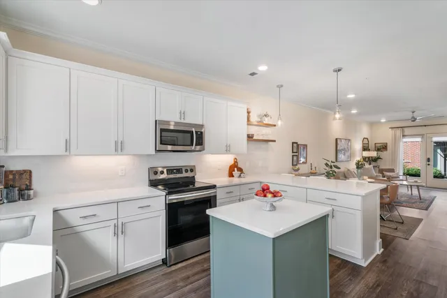 a kitchen with stainless steel appliances sink stove and white cabinets with wooden floor