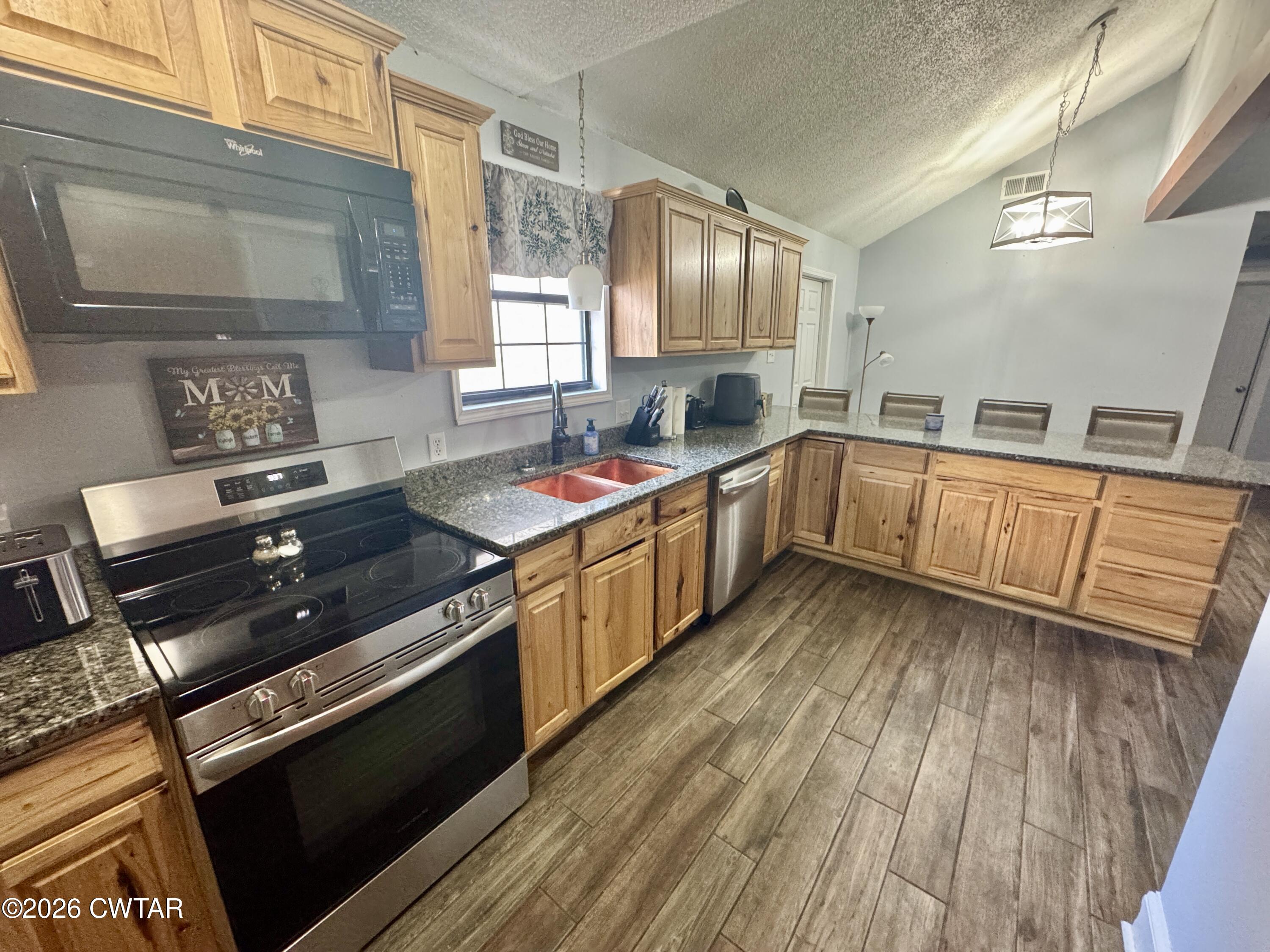 235 Tate Road Dyersburg, TN 38024 - Photo 15 of 34 a kitchen with stainless steel appliances a stove a sink dishwasher and cabinets with wooden floor
