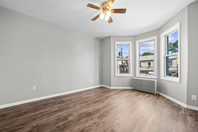 a view of an empty room with a window and wooden floor