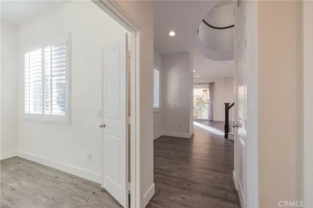 a view of a hallway with wooden floor and a bathroom