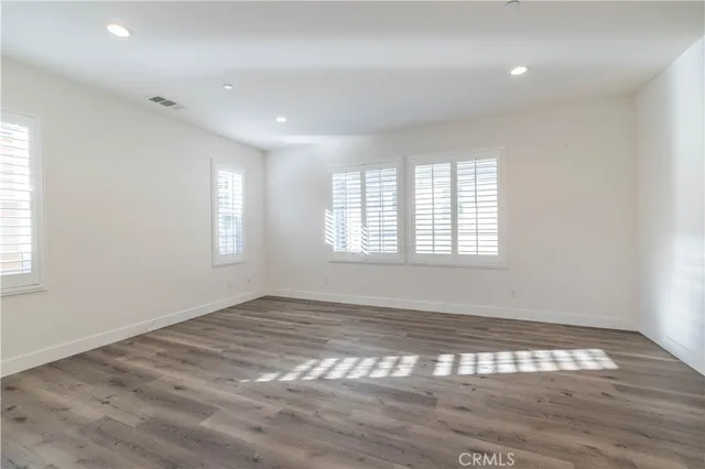 a view of an empty room with wooden floor and window