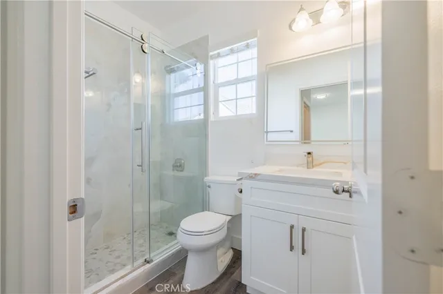 a bathroom with a shower sink vanity mirror and toilet