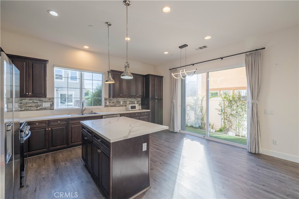 4 Lavanda Street Rancho Mission Viejo, CA 92694 - Photo 4 of 43 a kitchen with kitchen island granite countertop a stove a sink a center island and wooden floor