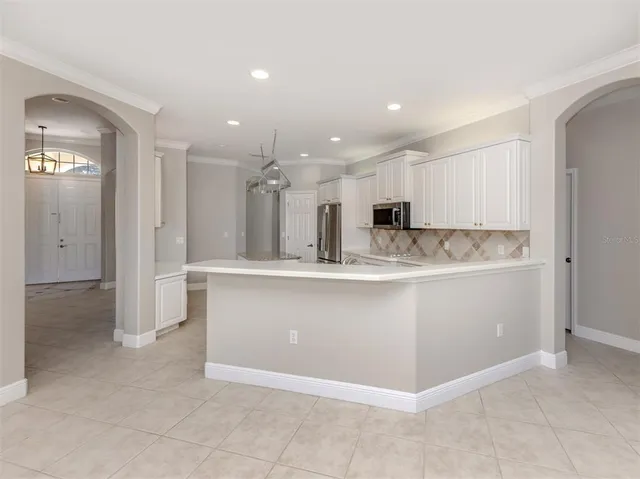 a kitchen with stainless steel appliances granite countertop a refrigerator a sink dishwasher a stove and white cabinets with wooden floor