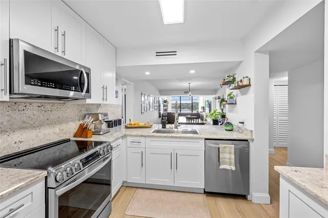 a kitchen with stainless steel appliances kitchen island granite countertop a stove and a sink
