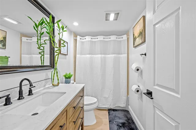 a bathroom with a granite countertop sink a toilet and shower