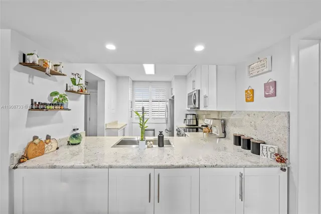 a kitchen with granite countertop a sink and a refrigerator