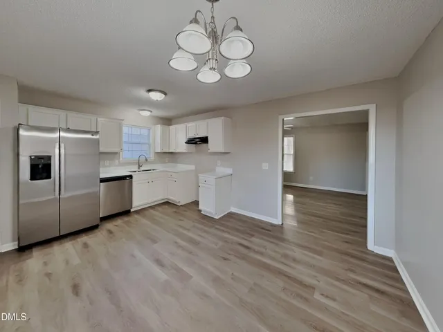 a view of a kitchen with a sink stainless steel appliances wooden floor and a large window