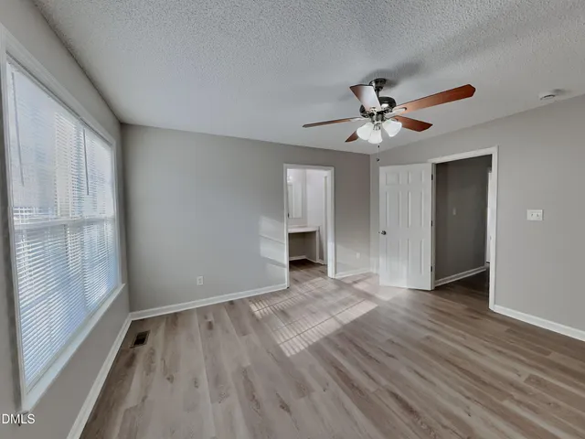 a view of empty room with wooden floor and fan