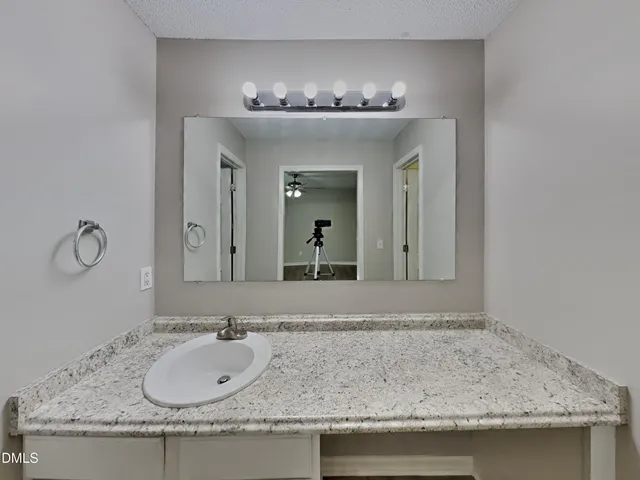 a bathroom with a granite countertop sink and a mirror