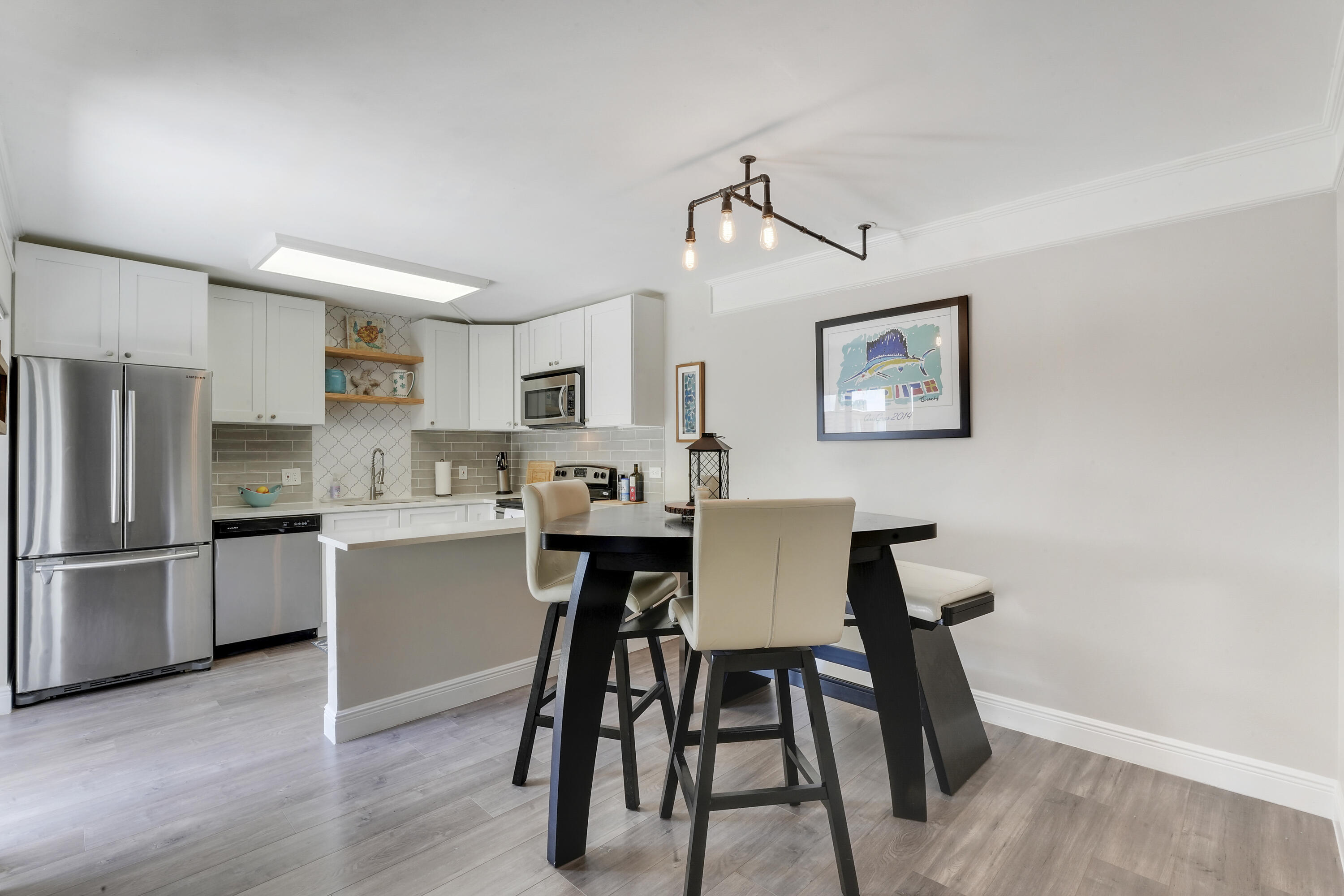 3900 County Line Road, Unit 4C Tequesta, FL 33469 - Photo 6 of 41 a kitchen with stainless steel appliances a dining table chairs and wooden floor