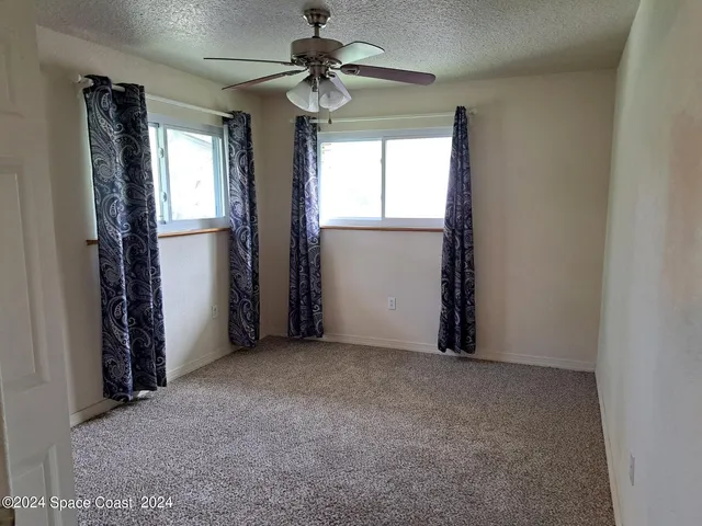 an empty room with windows and fan