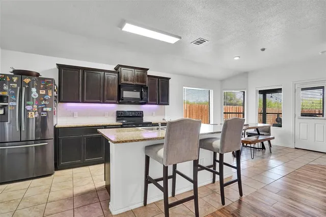 a kitchen with stainless steel appliances granite countertop a stove a refrigerator a kitchen island a table and chairs