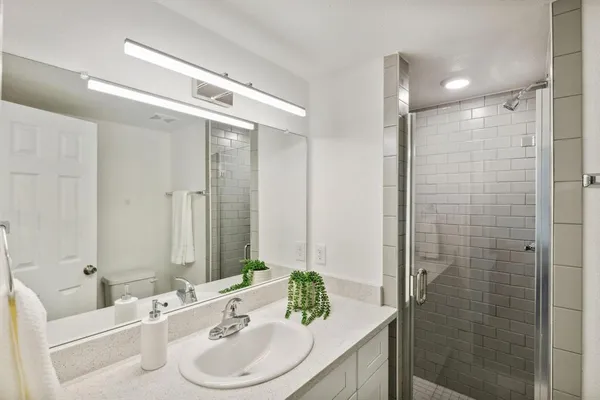 a bathroom with a granite countertop sink a shower and a mirror