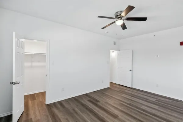 an empty room with wooden floor ceiling fan and windows