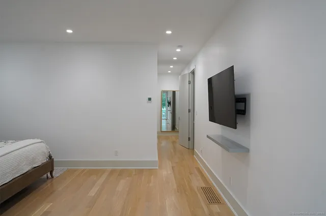 a view of hallway with wooden floor and flat screen tv