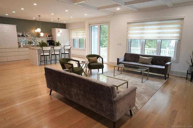 a living room with couches and kitchen view with wooden floor