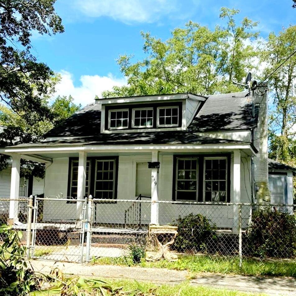 Bungalow-style home featuring covered porch, a gate, a fenced front yard, and a shingled roof