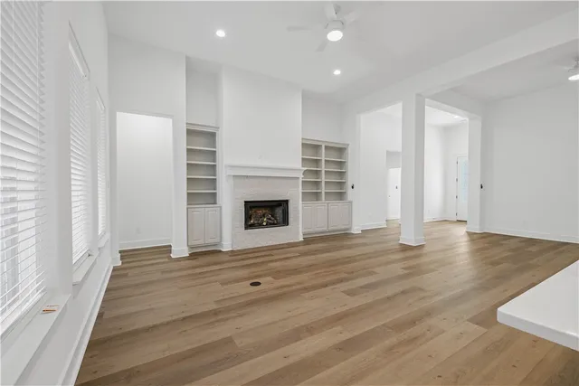 an empty room with wooden floor fireplace and windows
